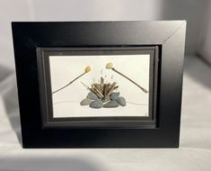 a black frame with some flowers and rocks in it