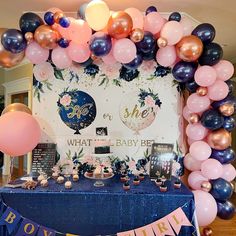 a baby shower party with balloons, streamers and decorations on a table in front of a wall