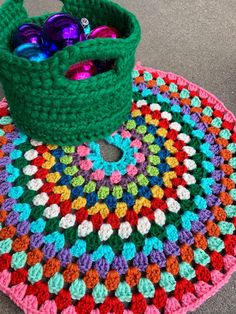 a crocheted table mat with a green basket filled with colorful eggs on it