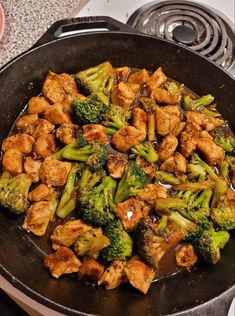 chicken and broccoli stir frying in a pan on the stove with sauce