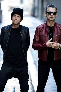 two men standing next to each other in the street wearing black and red leather jackets