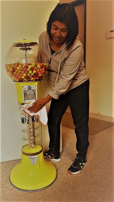 a woman standing next to a yellow gummy machine