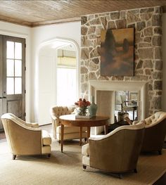 a living room filled with furniture and a fire place next to a stone wall covered in windows