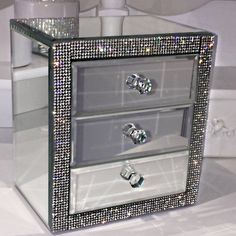 two drawers with diamonds on them sitting on a white counter top next to a vase