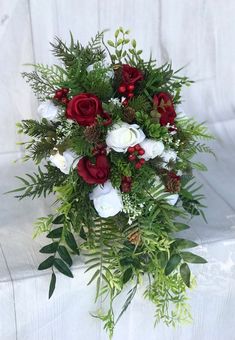 a bouquet of red and white flowers with greenery