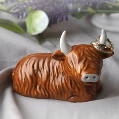 a ceramic cow with a ring on it's nose sitting on a white cloth