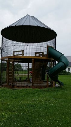 a play structure with a slide in the middle and a large mesh screen behind it