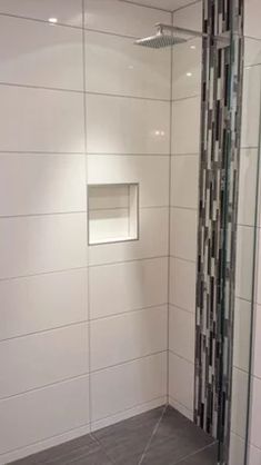 a walk in shower sitting next to a tiled wall