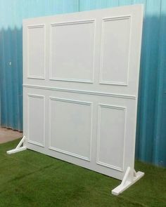 a large white bed frame sitting on top of a green grass covered floor next to a blue wall