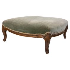 the footstool is made from wood and has a green upholstered cushion