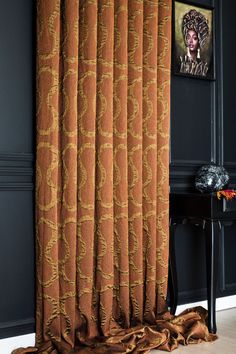 an orange curtain hanging in front of a black wall with pictures on the wall behind it