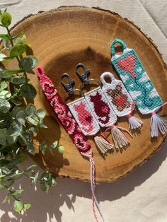 three crocheted scissors are sitting on a piece of wood next to a potted plant