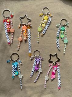 six keychains with beads and charms on them sitting on a cloth covered surface