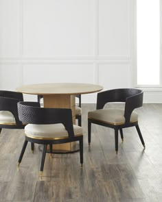 four chairs around a round table in a room with white walls and wood flooring