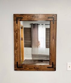 a mirror hanging on the wall above a sink in a room with white walls and wood trim