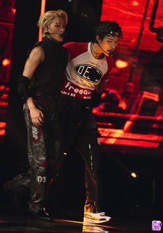 two people standing on stage with one holding the other's arm around his body