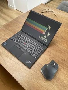 an open laptop computer sitting on top of a wooden desk next to a mouse and eyeglasses