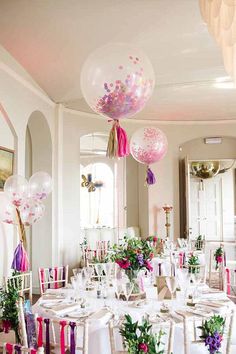 a room filled with lots of tables covered in white and pink decorations