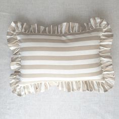 a striped pillow with ruffled edges on a bed