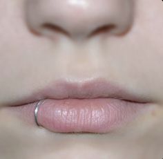 a close up view of a woman's lips with the lip ring on her nose