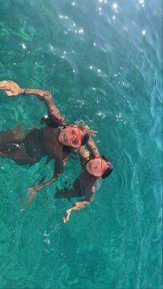 two people swimming in the ocean with goggles on