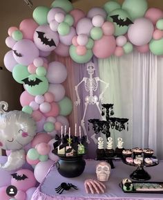 a table topped with lots of balloons and halloween decorations next to a wall filled with skulls