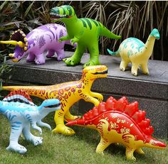 several plastic dinosaurs are lined up on the ground in front of some plants and bushes