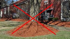 a red cross mark on top of a pile of mulch in front of a house