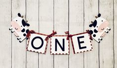 a cow banner with the word one hanging from it's side on a wooden wall