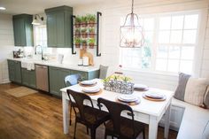 a kitchen and dining room with green cabinets, white counter tops and wooden floors is shown