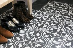 four pairs of shoes are lined up on the floor in front of a bench and tiled floor