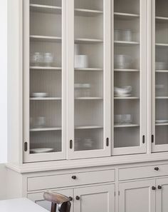 a white china cabinet with glass doors in the middle and drawers on both sides,