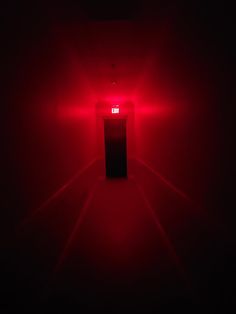 a red light in the middle of a dark room with only one light on it