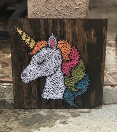 a string art unicorn on a wooden block