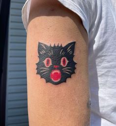 a black cat with red eyes and nose tattoo on the left upper half of the arm