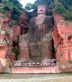 the giant buddha statue is surrounded by cliffs