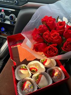 a bunch of roses and some chocolates in a box on a car seat next to a bouquet of red roses