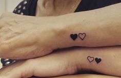 two people with matching tattoos on their feet, one is holding the other's hand