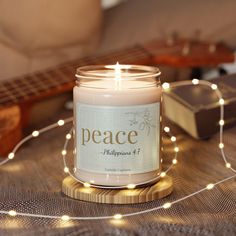 a candle sitting on top of a wooden table next to a string of lights and a guitar