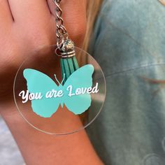 a person holding a keychain with a butterfly on it that says, you are loved