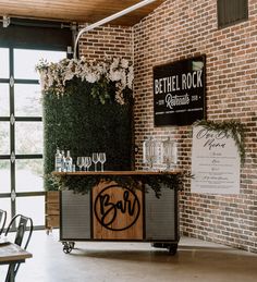 the bar is decorated with greenery and wine glasses