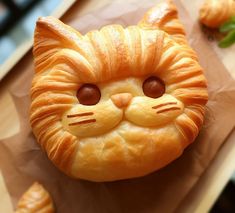 there is a pastry shaped like a cat on top of the table with croissants around it