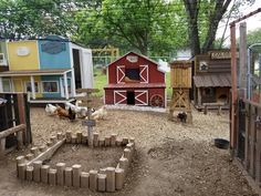 several chickens and roosters are in a small yard with many different colored buildings around them