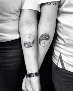 two people holding hands with tattoos on their arms