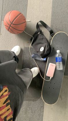 a skateboard, basketball and water bottle on the ground