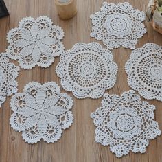 four crocheted doily sitting on top of a wooden table next to a vase