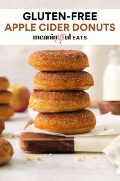 a stack of apple cider donuts on top of each other with apples in the background