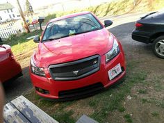 a red car is parked in the grass