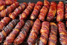 bacon wrapped sausages are cooking on the grill