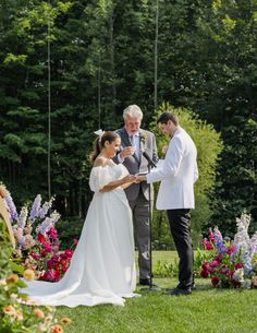 the bride and groom are exchanging their vows in front of an outdoor ceremony with colorful flowers